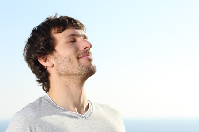 Close up of a man doing breath exercises outdoor with the sky in the background